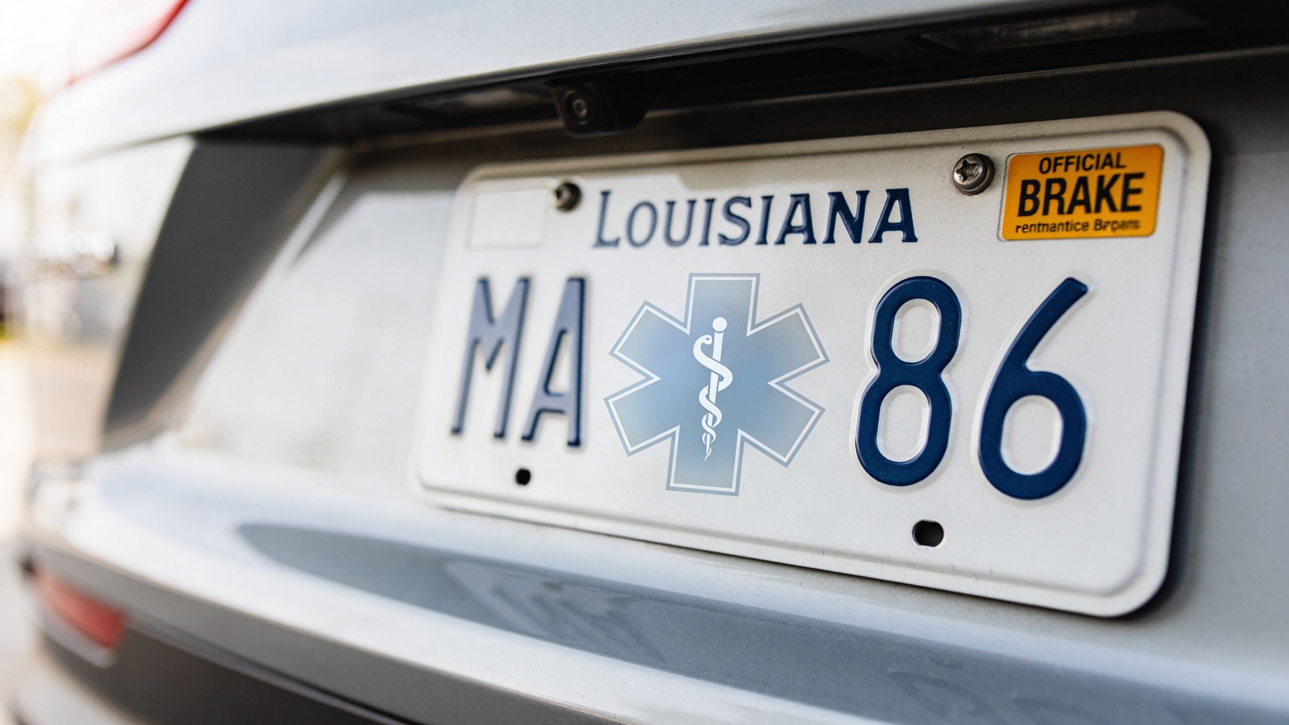A close up view of a Louisiana license plate featuring a medical symbol and an official brake tag.