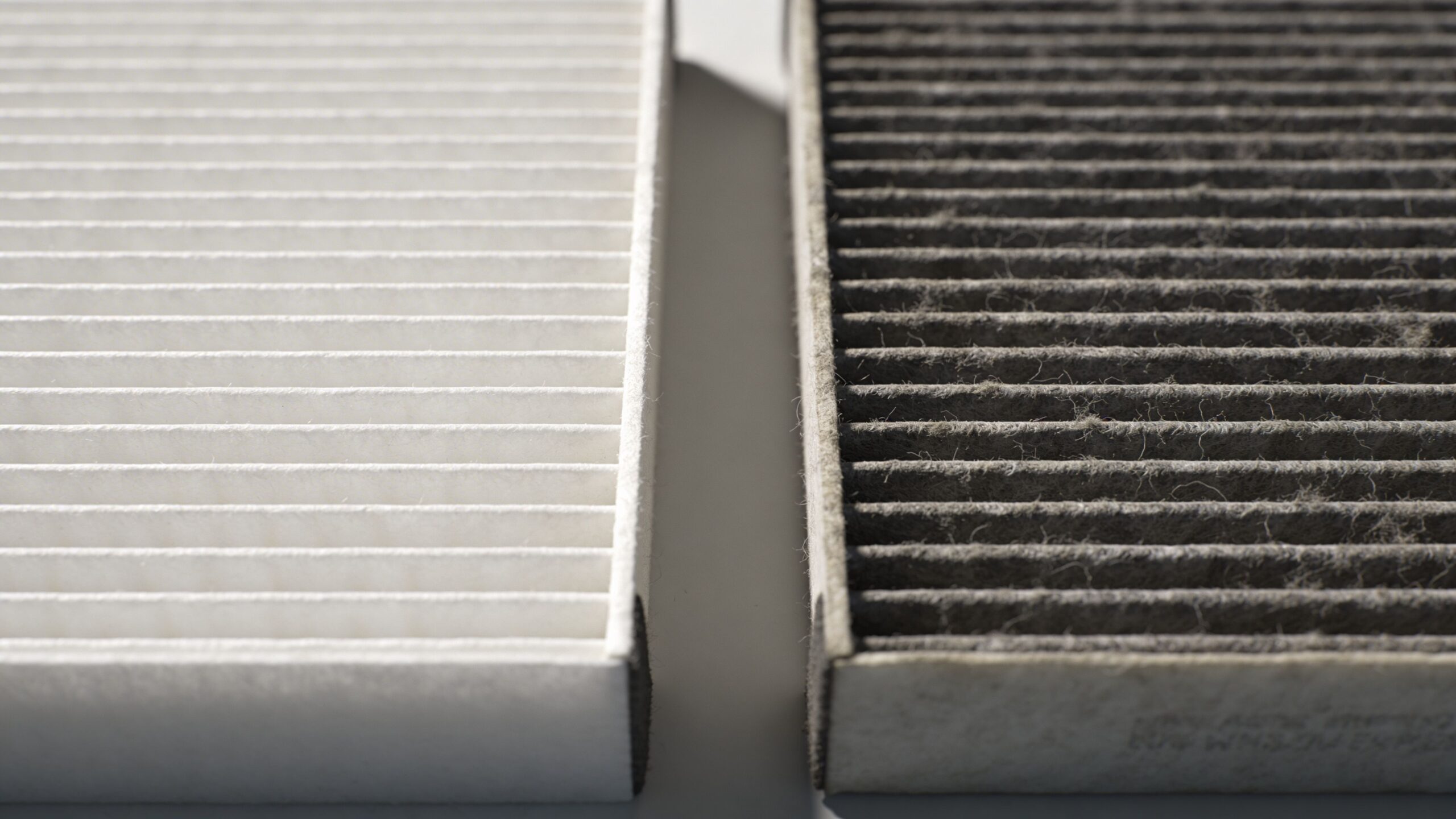 A side-by-side comparison of a clean new cabin air filter and a dirty, dust-covered used filter.