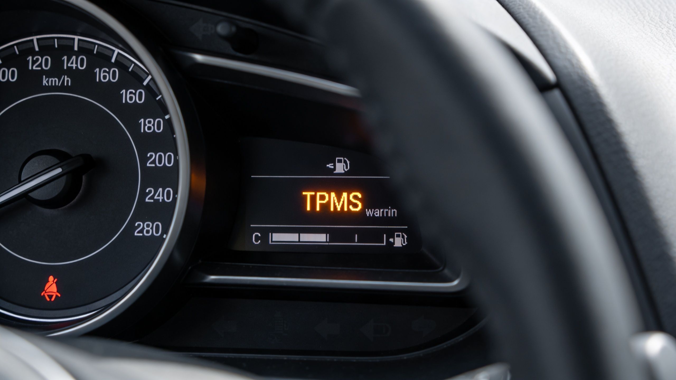 A car dashboard displaying a TPMS warning light indicating an issue with the tire pressure monitoring system.