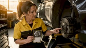 Female mechanic showing brake discount coupon near car brakes