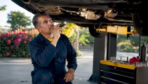 Mechanic inspecting repaired car parts undercarriage