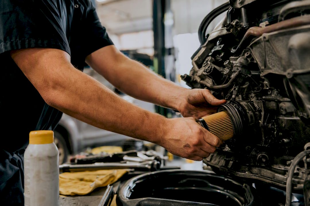 Hands removing oil filter during car maintenance
