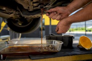 Technician draining transmission fluid under car