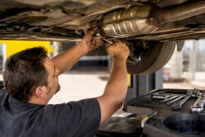 Technician hands removing catalytic converter