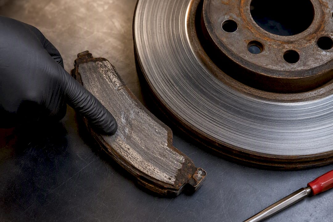 Worn brake pad beside scored rotor