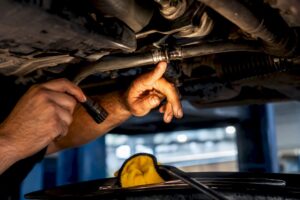 Technician inspecting power steering hose leak
